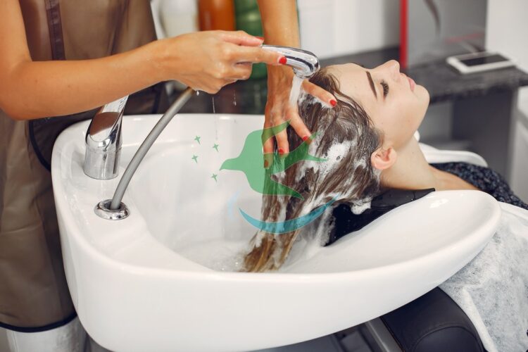 Hairdresser washing head her client. Woman in a hair salon